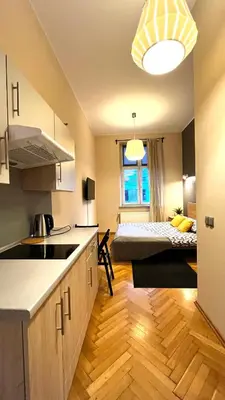 a kitchen with a room with a bed in the background at Double Studio City Center in Kraków