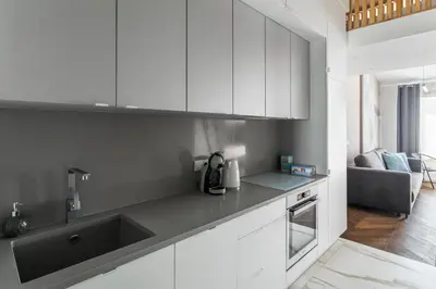 a kitchen with white cabinets and a black sink at Premium Apartment in Kossak Residence in Kraków
