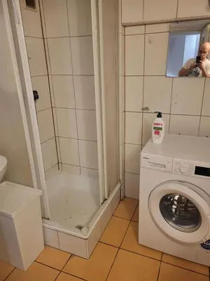 a man taking a picture of a bathroom with a washing machine at Grzegorzecka Room nr 1 in Kraków