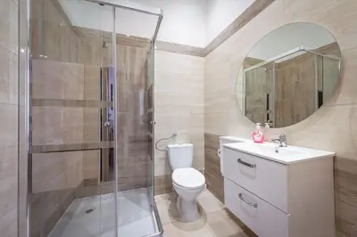 a bathroom with a shower and a sink and a mirror at 70s Hostel in Kraków
