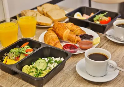 a table topped with trays of food and a cup of coffee at Kraków Trailside Apartments - by Upstairs in Kraków