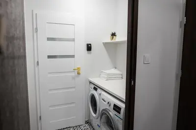 a laundry room with a white door and a washing machine at CracWoW K8 No.10 Apartment in Kraków