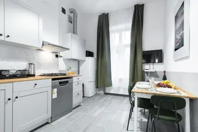a kitchen with white cabinets and a table with chairs at Wonderful Apartments in the Center of Krakow in Kraków