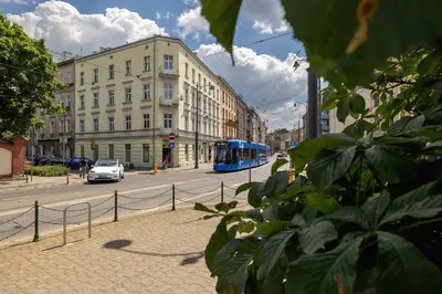 a blue bus driving down a city street with buildings at 1-Bedroom Apartment - 65 Długa Street in Kraków