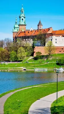 a building with a clock tower next to a body of water at Royal university apartment, Wawel castle in Kraków