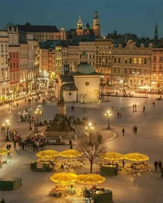 a city square with tables and yellow umbrellas at night at Air-conditioned apartment in the city center, Old Town in Kraków