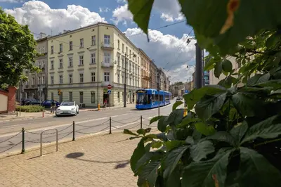 a blue bus driving down a city street with buildings at 1-Bedroom Apartment - Długa 65 in Kraków