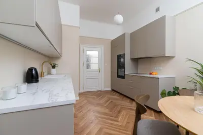 a kitchen with white cabinets and a wooden table at 2 - bedroom apartment - Rejtana 10 in Kraków