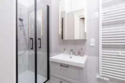 a white bathroom with a sink and a shower at 2 - bedroom apartment - Rejtana 10 in Kraków