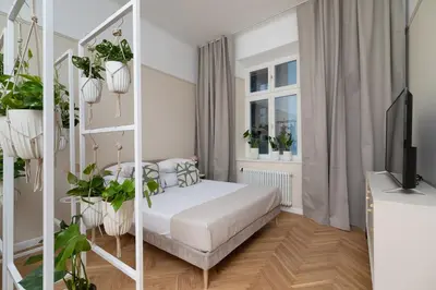 a white bedroom with a bed and plants at Apartment with balcony - Rejtana 10 in Kraków