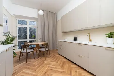 a kitchen with white cabinets and a table with chairs at Apartment with balcony - Rejtana 10 in Kraków