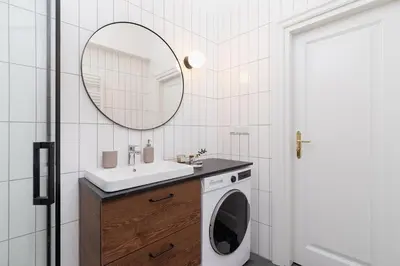 a bathroom with a washing machine and a mirror at 3 bedroom Apartment with the balcony - Rejtana 10 in Kraków