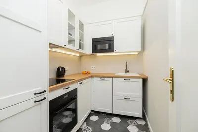 a small kitchen with white cabinets and a sink at 3 bedroom Apartment with the balcony - Rejtana 10 in Kraków