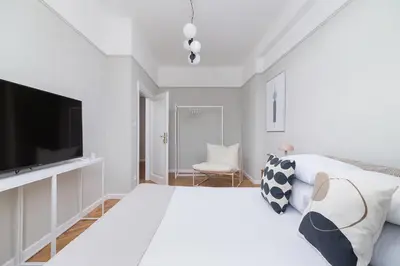 a white bedroom with a large bed and a flat screen tv at 2 - bedroom Apartment with balcony - Rejtana 10 in Kraków