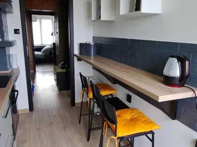 a kitchen with a counter with four stools at Green apartament in Oświęcim