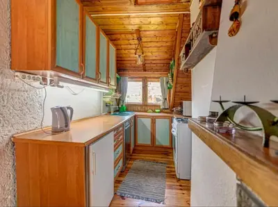 a kitchen with wooden cabinets and a wooden floor at Klimatyczny domek w górach in Sordelówka