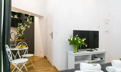 a living room with a television and a table with chairs at Old Town Apt - Wielopole studio W6 in Kraków