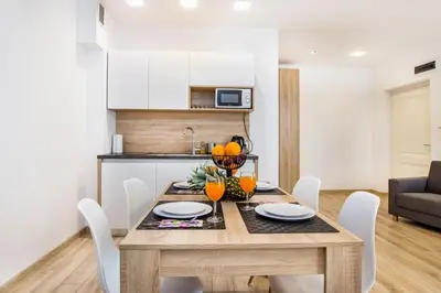 a dining room table with white chairs and a kitchen at Bosacka old town apt - B17 in Kraków