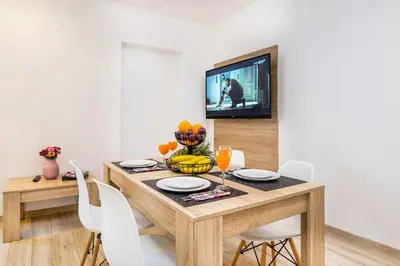 a dining room table with white chairs and a television at Bosacka old town apartment - B28 in Kraków