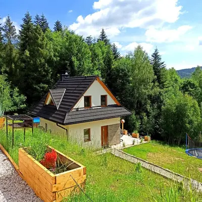 a house with a solar roof on top of a yard at Zawoja domki z jacuzzi, domek w stylu góralskim in Zawoja