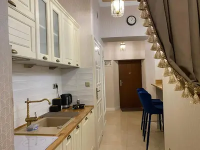 a kitchen with white cabinets and a sink and blue chairs at Radiance Residence Apartments in Kraków