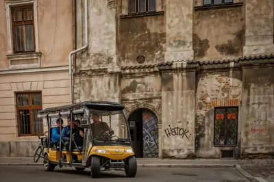 two people riding a golf cart in front of a building at Cracow Copernican Apartment #2 - Old Town in Kraków