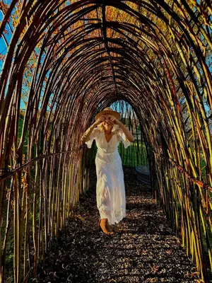 a woman in a white dress walking through a tunnel at Raj na Hektarach in Limanowa