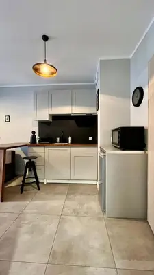 a kitchen with white cabinets and a table and a microwave at Small Studio in Kraków
