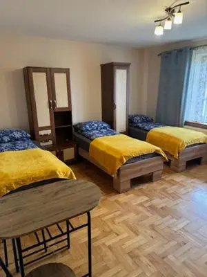 a room with three beds with yellow covers and a wooden floor at Bochnia ,nocleg, pokoje, kwatery pracownicze,dom in Bochnia