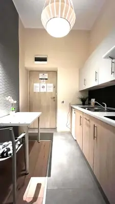 a kitchen with a table and a hallway with a door at Studio for One in Kraków