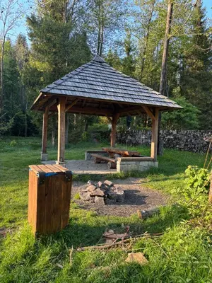 a wooden gazebo in a field with a fire pit at Apartament w Kocierzu in Kocierz Rychwałdzki
