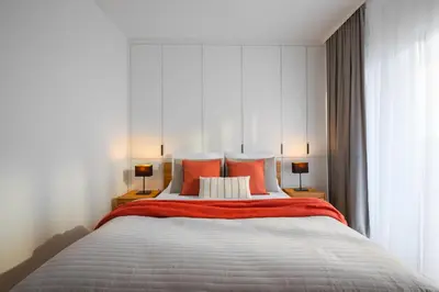 a bedroom with a large bed with orange pillows at Apartamenty Lew Invest obok Rynku Głównego, Parking w cenie in Kraków