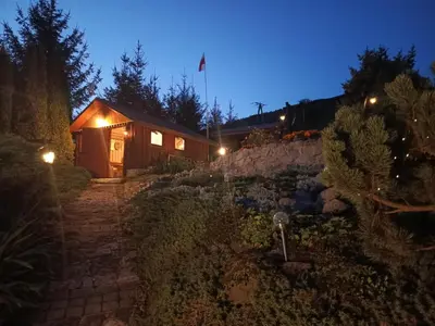 a wooden cabin with lights in a garden at night at Dom w Chomranicach-domek grillowy in Chomranice