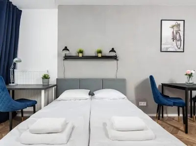 a bedroom with a bed and two blue chairs at Nowoczesny apartament nad Wisłą in Kraków