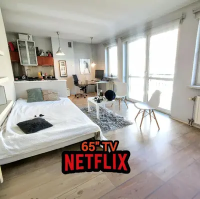 a bedroom with a large bed and a living room at Cozy Studio for a Couple - 10 min from the airport in Kraków