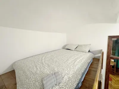 a bed in a room with a white wall at Batory's Tavern in Kraków