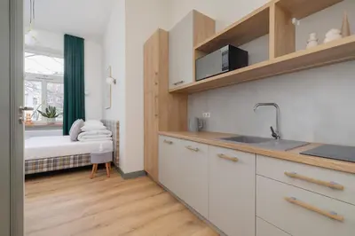 a kitchen with white cabinets and a bed in a room at Studio for 2 - Augustiańska 1 - Kazimierz in Kraków