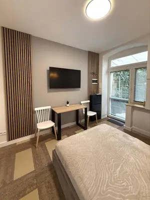 a bedroom with a bed and a desk and a television at Modern studio Old Town Railway Station in Kraków