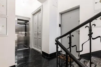 a hallway with white walls and a staircase with a metal railing at Old Town 5min Main Market Square Perfect Apartment AC WiFi Parking Balcony in Kraków