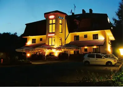 a white car parked in front of a building at night at Hotel Twardowski in Głogoczów