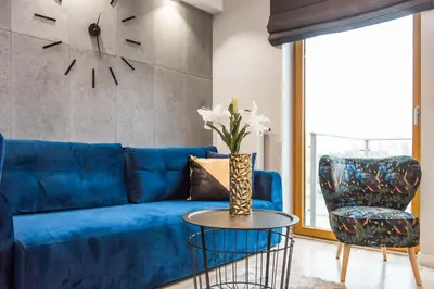 a blue couch and a chair in a living room at Bed&Bath Luxury Apartments in Kraków