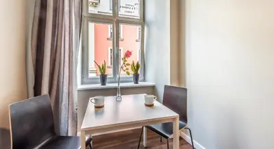 a table and two chairs in a room with a window at Flamingo Premium Hostel in Kraków