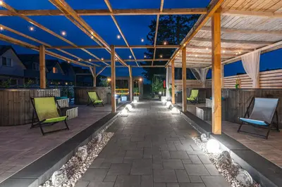 an outdoor patio with chairs and lights at night at Old Tree Village & Restaurant in Oświęcim