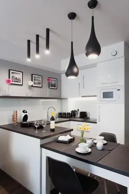 a kitchen with white cabinets and a table with chairs at City Point Apartment Old Jewish Quarter in Kraków