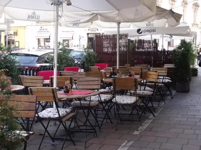a row of tables and chairs under an umbrella at Apartment for guests (1) in Kraków