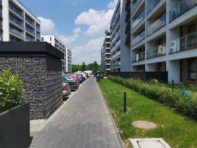 a sidewalk next to a parking lot with parked cars at Apartament Kraków Arena in Kraków