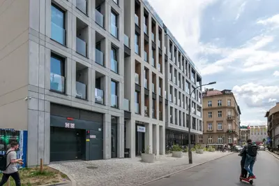 a man riding a skateboard down a street next to a building at In City Apartments Rajska 3 in Kraków