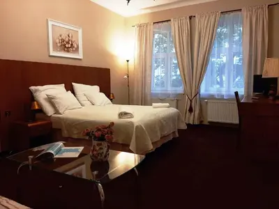 a bedroom with a bed and a table and windows at Red Carpet Premium in Kraków