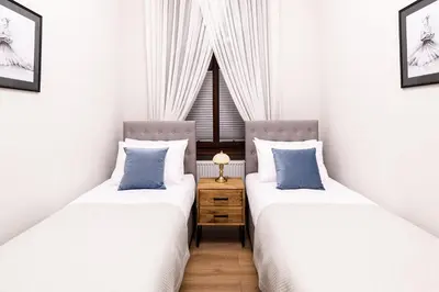 two twin beds in a room with a window at Apart Residence Ariańska 16 by NEARTO PL in Kraków