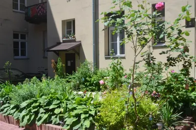 a garden in front of a building with flowers at Apartament Moments Stare Miasto Style and Comfort Netflix in Kraków